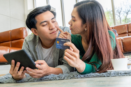 年轻夫妇在家中的互联网站上使用信卡在线购物信用卡号码是假冒的信用卡上没有个人信息网上商业购物概念图片