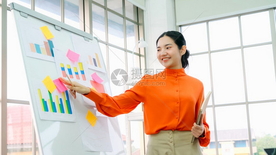 年轻女在临时办公室的白板上解释商业数据图片
