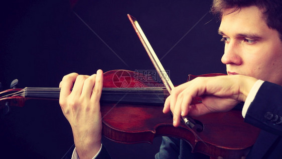 音乐激情爱好概念把穿着优雅小提琴的年轻人关起来把黑背景的摄影棚拍下来把穿着优雅小提琴的男子拍下来把穿着优雅小提琴的男子拉起来图片