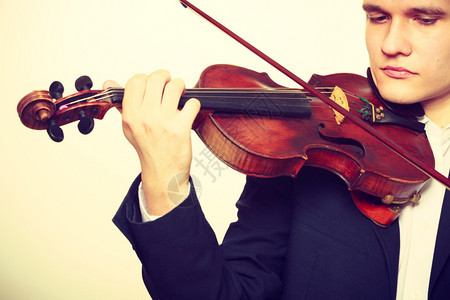 音乐激情爱好概念年轻人穿着优雅的木小提琴演奏工作室拍的白色背景男人穿的优雅小提琴演奏图片