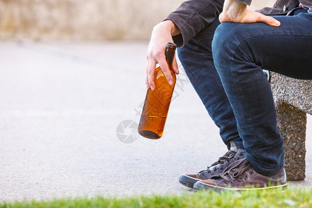 一个人在户外的长椅上喝着酒瓶子一个人在户外的长凳上喝着酒瓶子图片