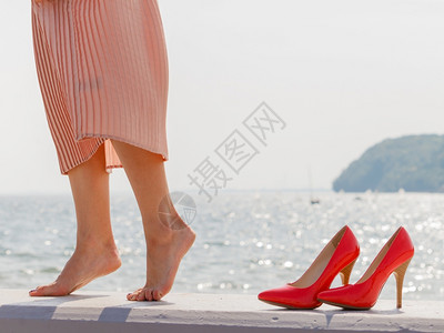 妇女穿着漂亮的长粉红裙子高跟鞋站着的nex对腿穿着长的粉红色裙子妇女在码头上行走图片