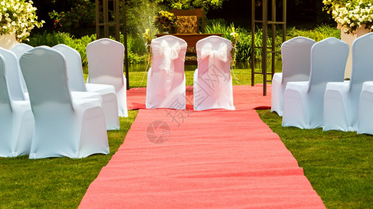 许多婚席在绿草和长的红地毯上盖着白色优雅的封面配偶在中间图片