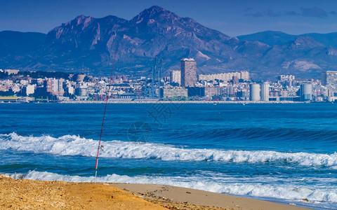 岸边的海钓鱼棒远处阿利坎特城西班牙的科斯塔布兰卡海滩上的钓鱼棒设备图片