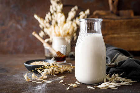 以玻璃瓶和烹饪用原料装的维加燕麦健康的素食非乳品饮料或替代牛奶背景图片