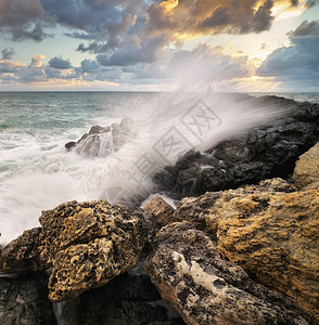 美丽的海景暴风雨中的海浪日落时会喷洒到石头上自然的构成图片