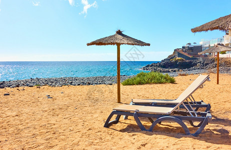 在阳光明媚的夏日桑迪海滩上有阳伞和光沙滩海边有阳伞和日晒图片