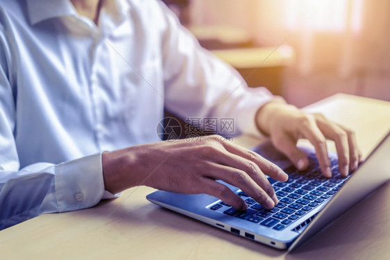 商人在办公室一台笔记本电脑的键盘上打手字图片