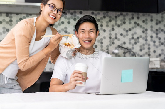 亚洲夫妇在厨房家工作吃送餐人取走食物和咖啡而城市则被封锁远离科罗纳新冠virus新冠19的流行图片