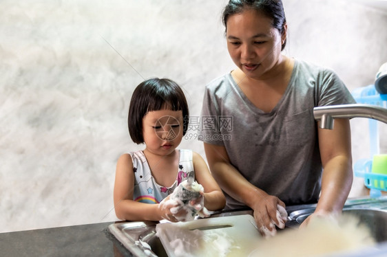 亚洲女孩与母亲一起洗盘子和餐具儿童家务使发挥行政职能家庭工作是为了孩子的生活方式和家庭概念图片