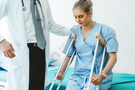 医生照顾院的拐杖病人理疗师和腿部受伤康复概念图片