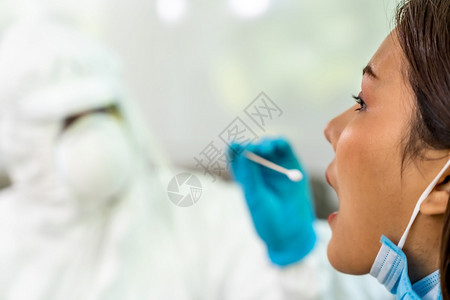 个人防护设备服检验科罗纳coronaviruscovid19的医疗人员在家里通过喉咙网向亚裔妇女进行检测在家中和医疗分娩方面提供图片