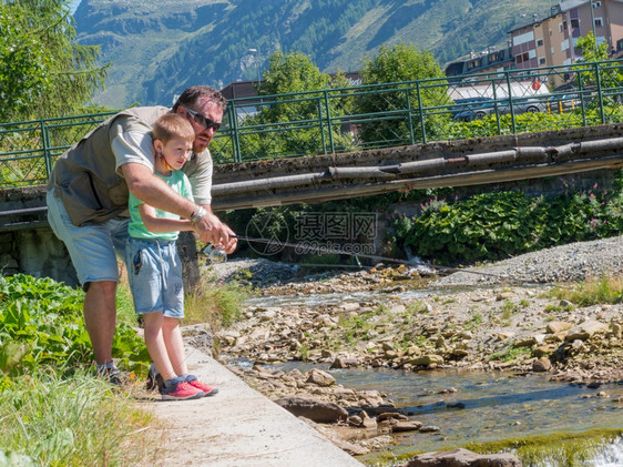 父亲在山上河边教小男孩钓鱼图片