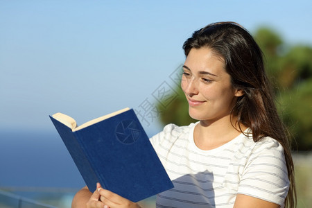 快乐的女人在酒店阳台上看书图片