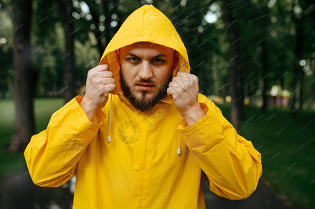 穿着雨衣的男子在天夏季公园戴上头罩独自一人穿着雨披风的男子在行走