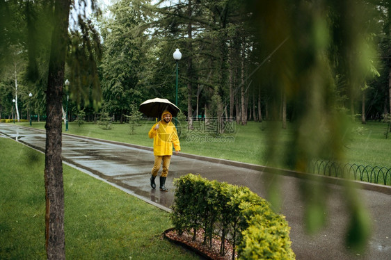 雨天衣和橡皮靴巷子里的湿天气孤独自一人在公园雨日独自一人带着伞在公园行走图片