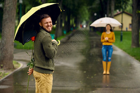 下雨天情侣拿着玫瑰花在公园约会背景图片