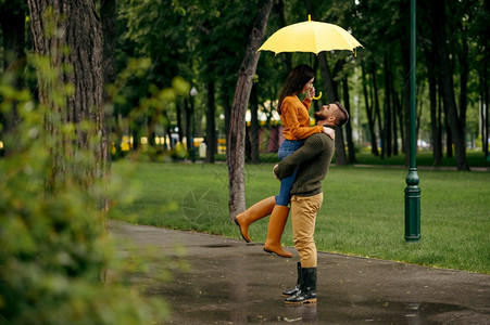 男人和女在雨伞下拥抱浪漫的约会在路上小巷里湿的天气图片