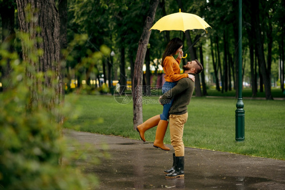 男人和女在雨伞下拥抱浪漫的约会在路上小巷里湿的天气图片