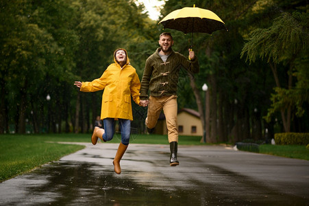 欢乐的情侣撑伞在公园玩耍跳跃图片