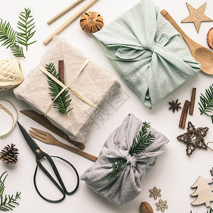 包装成的礼品和木制圣诞装饰可再使用的持续利生纺织礼品包装替代零废物概念平铺顶视图片