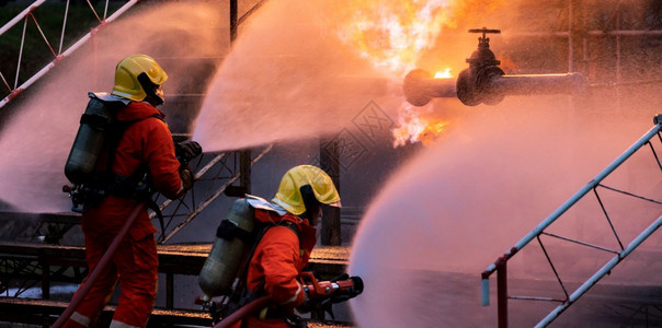 全景消防队使用水雾喷射灭火器来对付石油管道泄漏和钻机天然气站爆炸造成的火焰图片