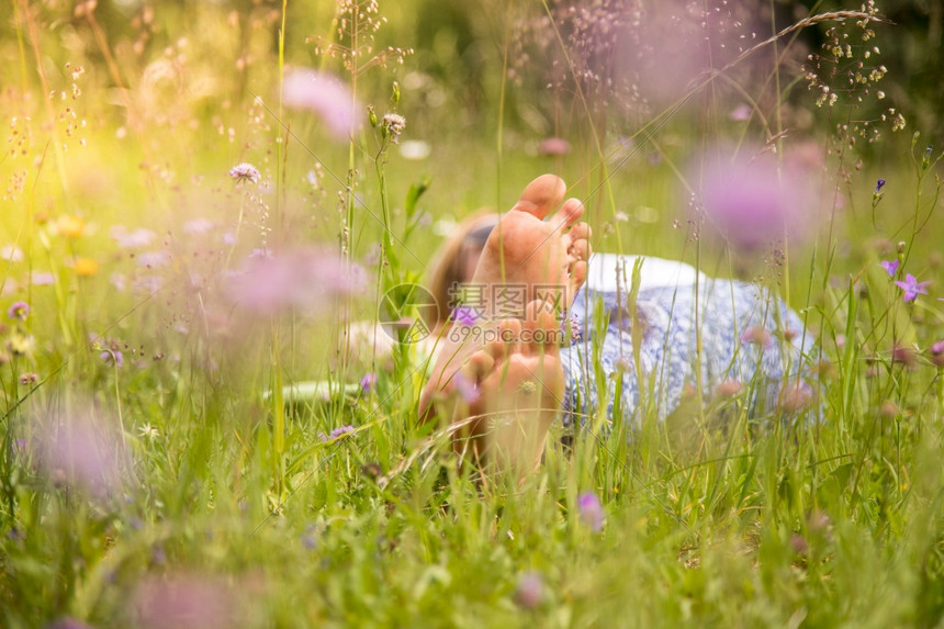 公园里的年轻女孩躺在草地上享受着白天图片