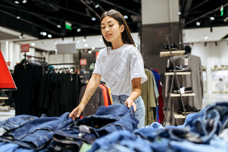 女在服装店中选择牛仔裤女在时装店商购物女在服装店购买时物观光图片