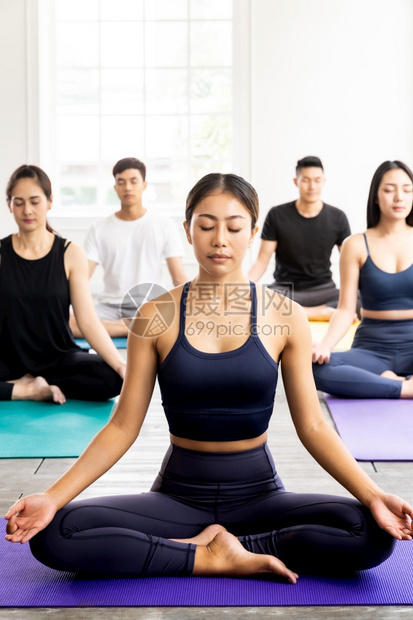 身穿运动服胸裤在莲花上练习瑜伽课的运动型有吸引力的亚洲人群体在用教练座上担任帕德马萨纳教席图片