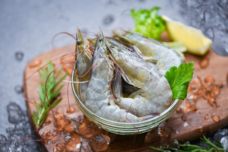 碗上新鲜虾和配有迷迭香成分药草和料的木制切菜板供做饭的海产食品在餐厅冷冻的冰面上生虾图片