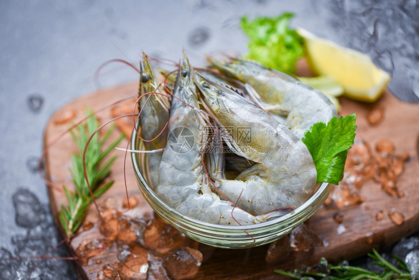 碗上新鲜虾和配有迷迭香成分药草和料的木制切菜板供做饭的海产食品在餐厅冷冻的冰面上生虾图片