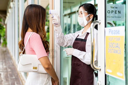 亚洲女服务员在进餐前面给女顾客测量温度图片