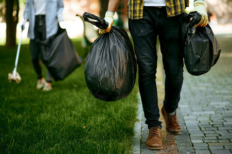 青年男子在公园中持有塑料垃圾袋从事志愿工作男子清洁森林生态恢复活方式垃圾收集和回生态护理图片