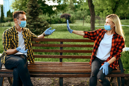 戴面罩的情侣和手套坐在公园的长椅上检疫流行病期间的浪漫会议保健和护流行生活方式戴面罩的情侣坐在长凳上检疫戴面罩的情侣坐在长凳上检图片