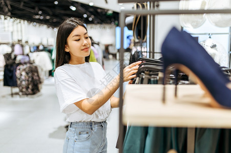 在服装店里选鞋的漂亮女人在时装店商购物的漂亮女人在鞋店里选的漂亮女人在靴子上看滑的漂亮女人在服装店里选鞋的漂亮女人图片