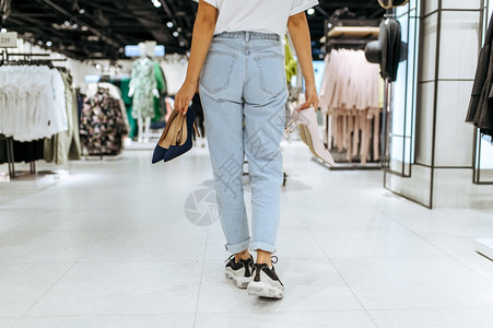 年轻女在服装店后视和都有多双鞋女在时装店商购物偷看靴子年轻女在服装店有多双鞋图片