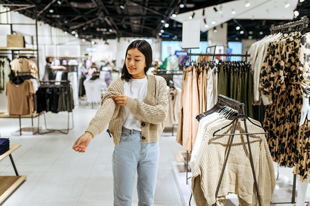 女青年在服装店试穿羊毛衫女青年在时装店商购物观光买衣服女青年在装店试穿图片