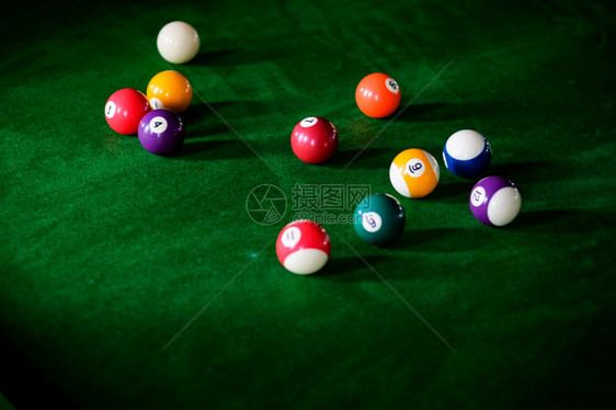 Man手和Cue臂在玩Snooker游戏或准备在绿色球桌上绿色盘上有多彩的Snooker球图片