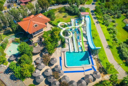 游泳池水公园在透明蓝水中游泳的人雨伞防晒床日落绿树暑假水公园最优视滑板豪华度假胜地的闲暇图片