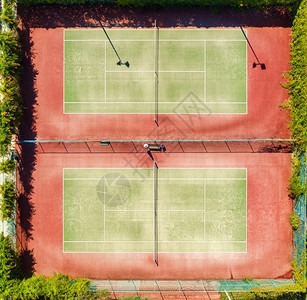 夏季日落时的网球场空中景象绿色网球场飞行无人驾驶机的顶级景象从阳光明媚的日天运动训练场的顶级景象背和概念运动区图片