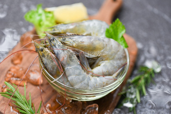 海产食品餐厅冰冻的生虾碗上新鲜和配有迷香成分药草和烹饪海产食品香料的木制剪板图片