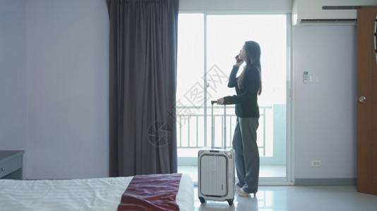 在酒店卧室使用智能手机或的亚洲泰国女商人图片