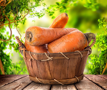 一篮子里新鲜的胡萝卜放在木制桌上的一篮子蔬菜作物图片