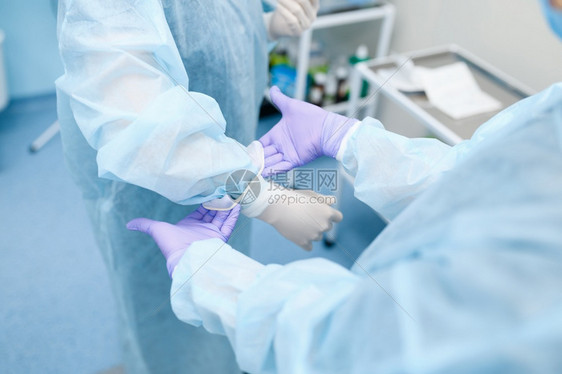 女外科医生和助理在手术室戴上套准备外科术穿制服的医生疗诊所工作人员医药和保健院的图片