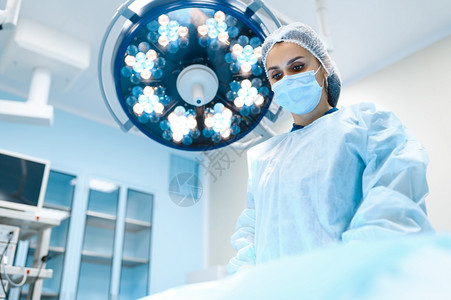 手术室背景灯外科手术穿制服的医生疗诊所工作人员医药和保健院的手术室穿礼服和戴面罩的女外科医生图片
