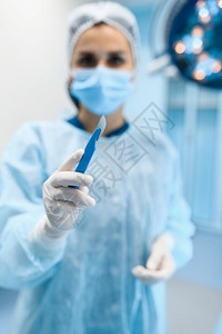 穿礼服和戴面罩的女外科医生展示手术室的外科背景灯外科手术穿制服的医生门诊外科和保健院的图片