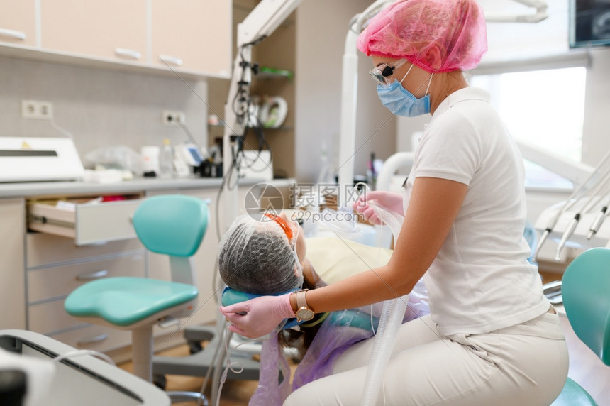 女牙医戴面罩坐在椅子上的病人口腔诊所穿制服的医生务工作者口腔医生药和保健专业口腔护理和卫生牙医病人坐在椅子上图片