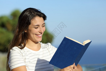 快乐的女人在酒店阳台上看书图片
