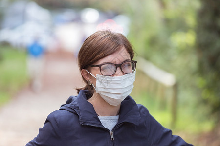 身戴面罩和眼镜被玷污的户外青年妇女图片