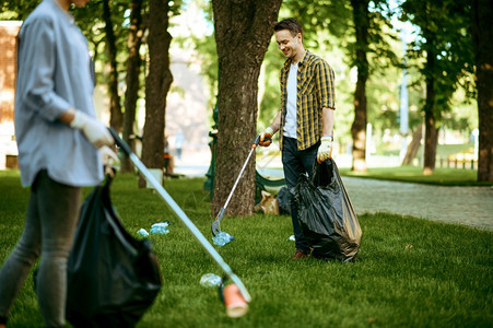 两人在公园的袋子中收集塑料垃圾从事志愿工作男子清洁森林恢复生态活方式垃圾收集和回生态护理环境清洁两人收集塑料垃圾志愿工作图片